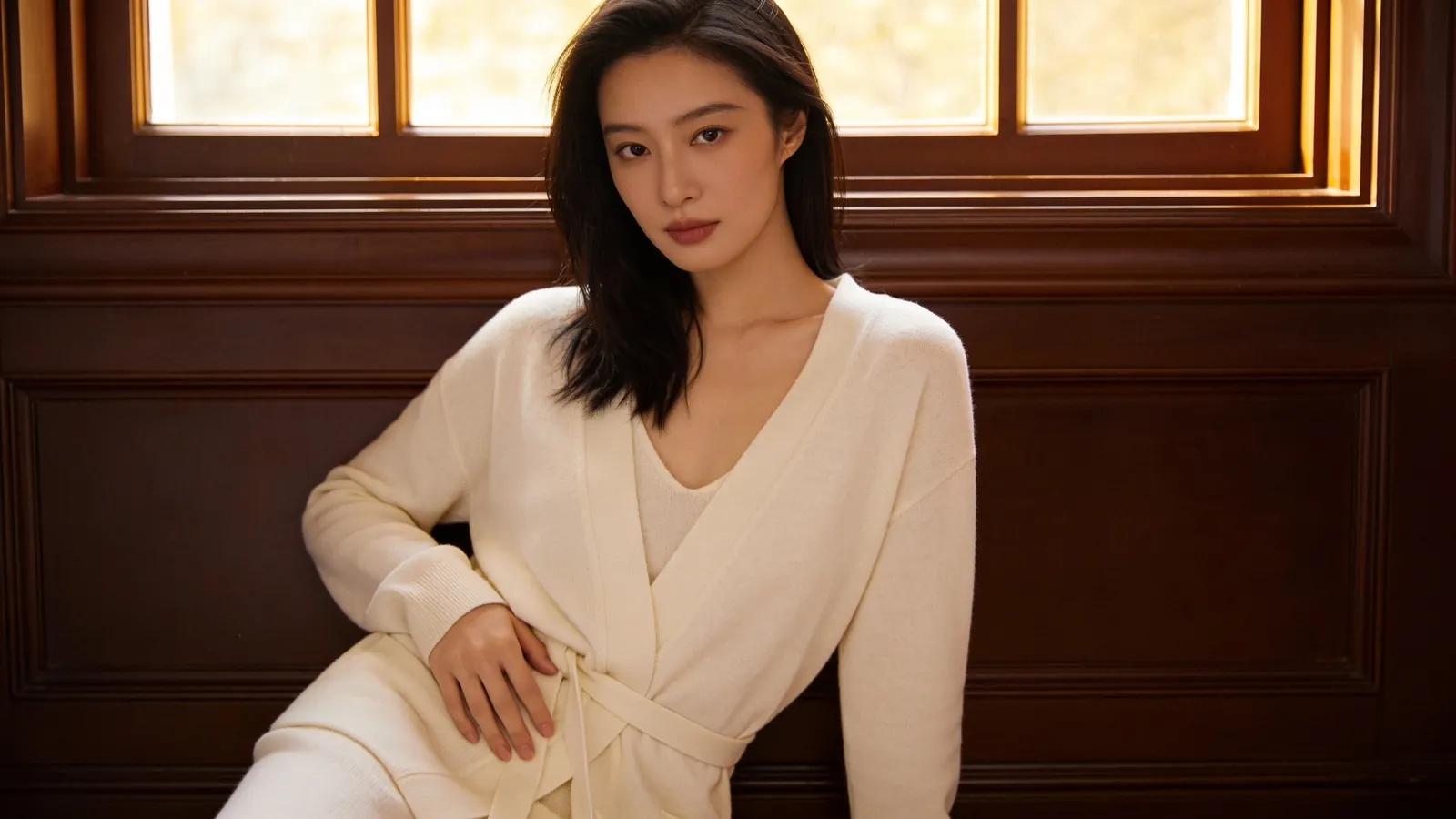 An East Asian woman in cream loungewear resting her hand on her side at the waist — illustrative image