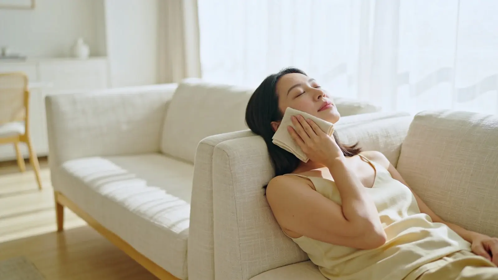 Illustrative image, not a patient: a woman at home holds a cool compress lightly near her cheek