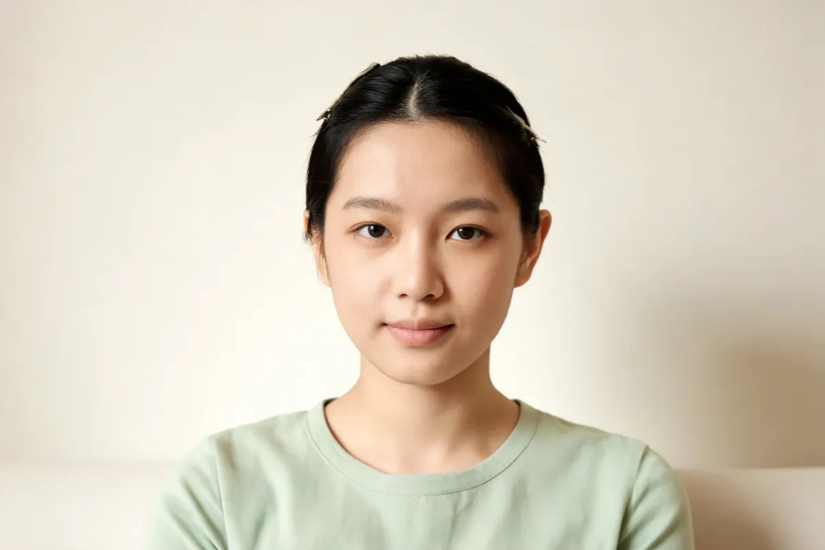 A woman in her twenties without make-up, hair clipped back, in gentle side light (illustrative image, not a patient)