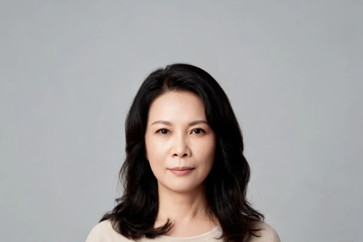 A woman in her forties with a calm expression against a grey backdrop (illustrative image, not a patient)