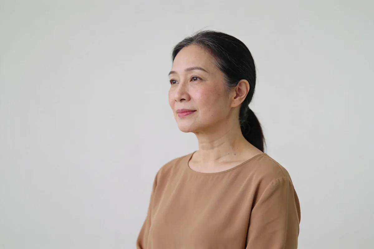A woman in her forties in three-quarter view with soft light on the cheekbone (illustrative image, not a patient)