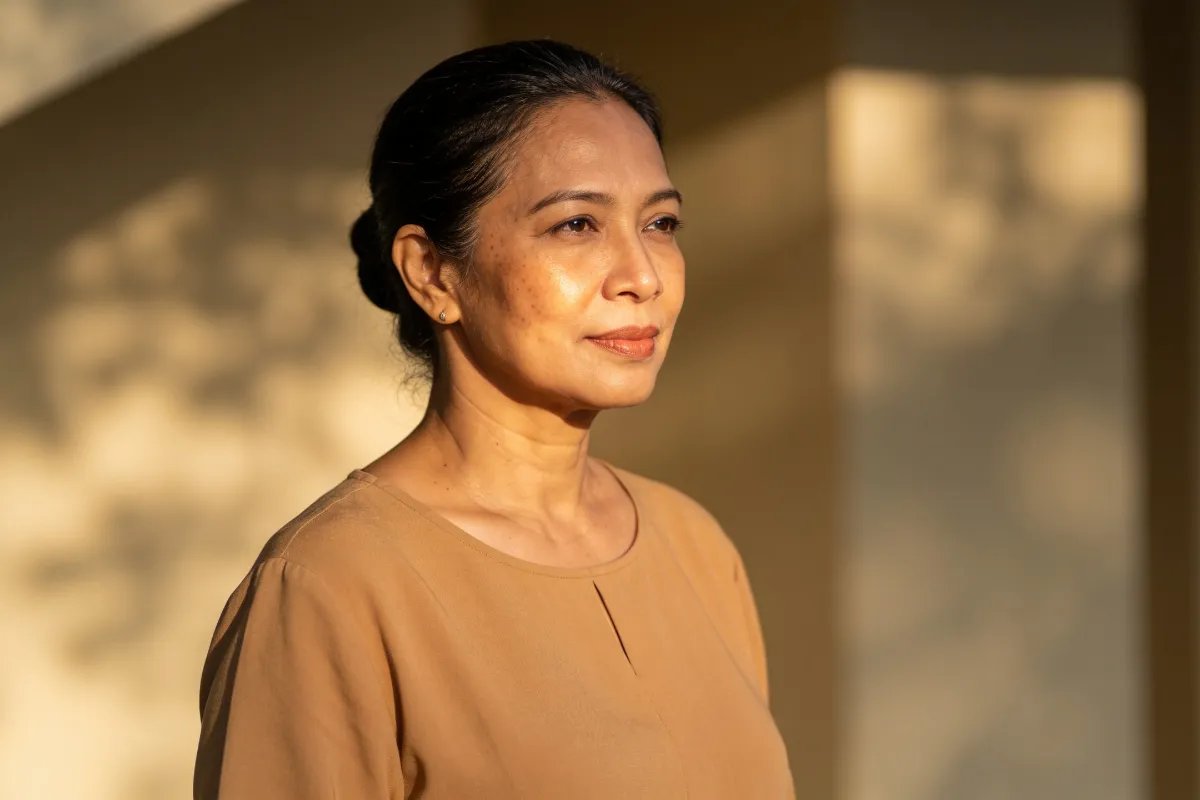 A woman in her forties in three-quarter view with soft light on the cheekbone (illustrative image, not a patient)