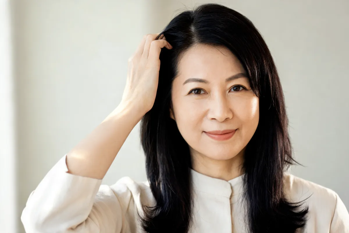 A woman in her forties running her fingers through her dark hair (illustrative image, not a patient)