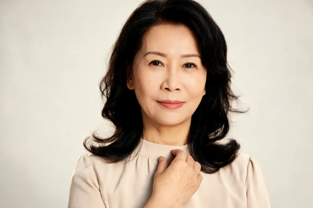 A woman in her fifties with a hand resting at her collarbone (illustrative image, not a patient)