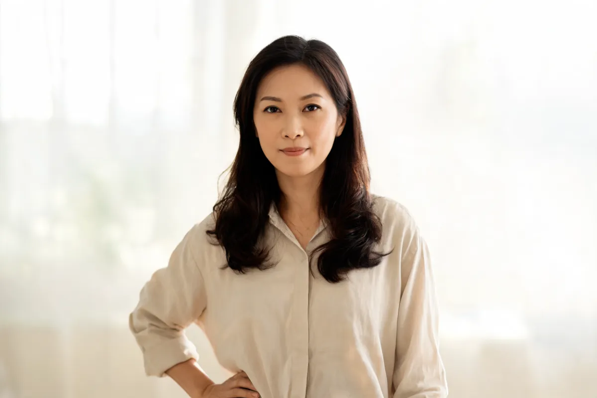 A woman in her thirties in a loose shirt with a hand on her hip (illustrative image, not a patient)