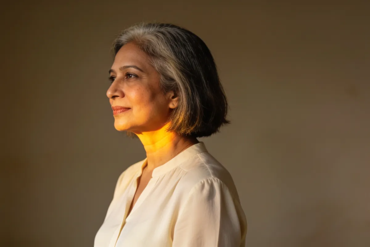 A woman in her fifties with a grey-streaked bob, face turned toward warm side light (illustrative image, not a patient)