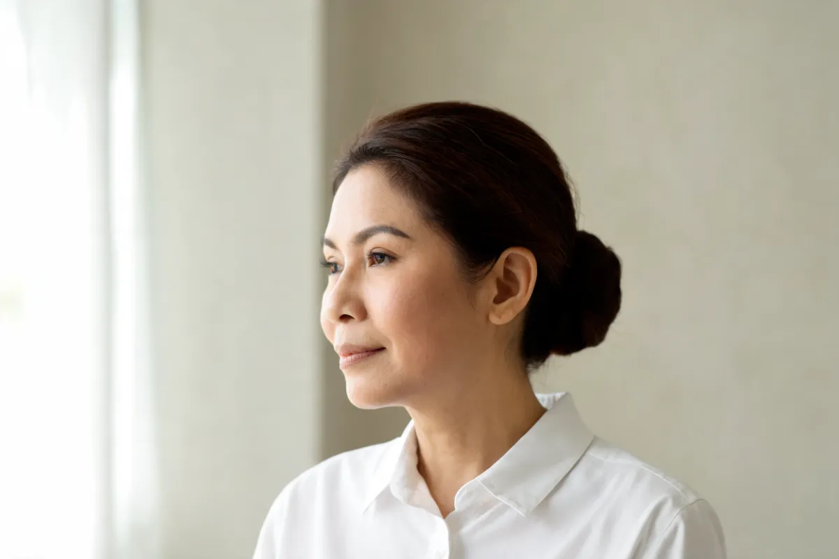 A woman in her forties with her jawline turned toward soft light (illustrative image, not a patient)